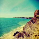 Photographie de l'océan atlantique vue d'une falaise. Le sable doré, les vagues.
