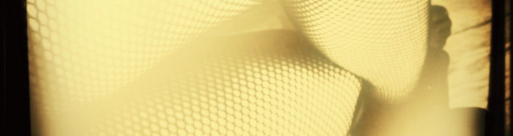 Photographie des jambes croisées d'une femme en bas résille assiste à la terrasse d'un café.