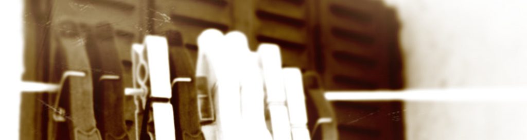 Photographie d'une pinces à linge accrochées sur un fil près d'une maison aux volets clos.