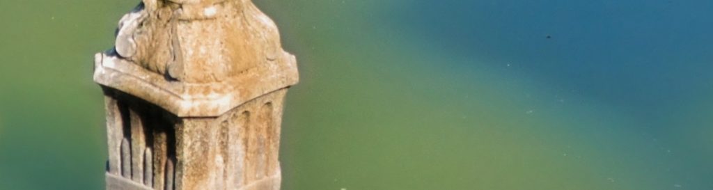 Photographie d'une lanterne au milieu d'un bassin ou se reflètent la cime des arbres.