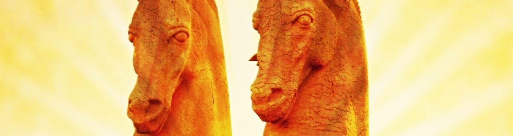 Photographie d'une statue de deux chevaux majestueux orange cabrés vers le ciel.