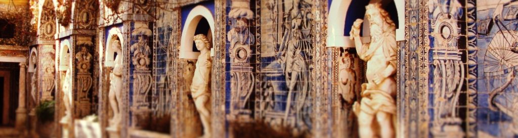 Photographie d'une allée bordée de statue en pierre et d'azulejos bleu et blanc.