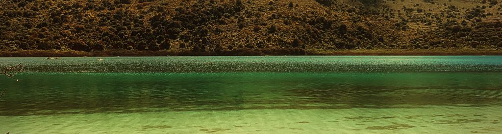 Photographie d'un lac entouré de montagnes arides. L'eau est claire, transparente et fraiche d'un bleu turquoise intense.