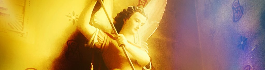 Photographie d'une statue en bois d'un archange terrassant un serpent avec sa lance.