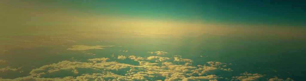 Photographie d'un ciel bleu rempli de nuages blancs prise du hublot d'un avion.