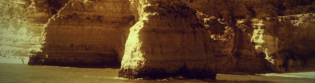 Photographie de falaise blanches et dorées bordées par l'océan atlantique.
