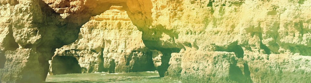 Photographie d'une falaise blanche qui forme une arche au milieu de l'océan.
