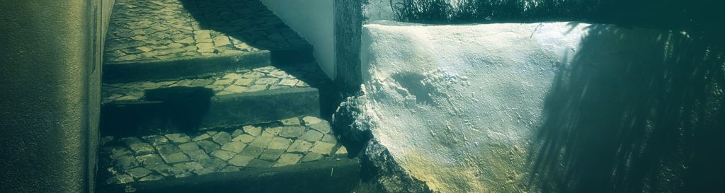 Photographie d'une ruelle étroite dans le village de Salir. Le sol pavé de petits carreaux en pierre noire et blanche.