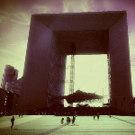 Photographie de la grande arche de la Défense avec le soleil qui se reflète sur la structure.
