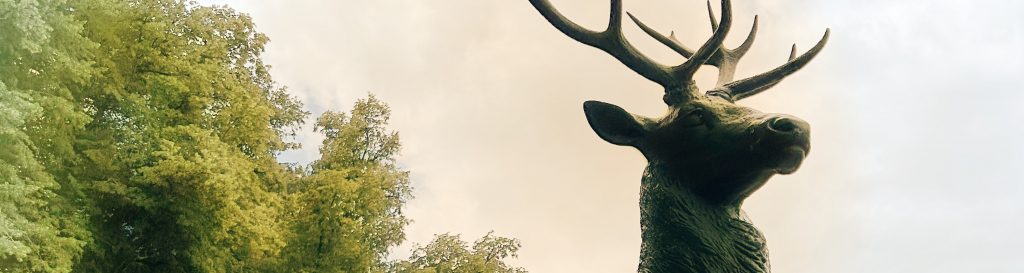 Statue artistique d'un cerf couché dans le parc du château de Rambouillet, capturant l'élégance et la majesté de la nature dans un cadre verdoyant.