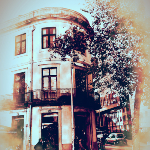 Photographie d'un appartement à Porto. La construction est ancienne, les murs de formes arrondie. un arbre cache la lumière du soleil.