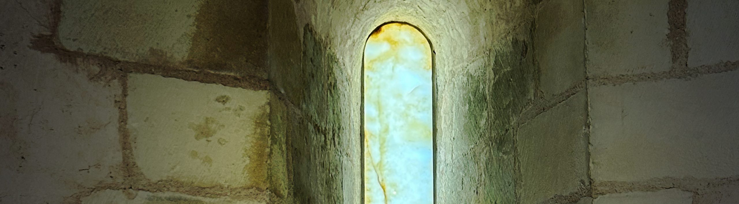 Photographie d'une meurtrière du château de Falaise laissant passer une lumière bleuté.